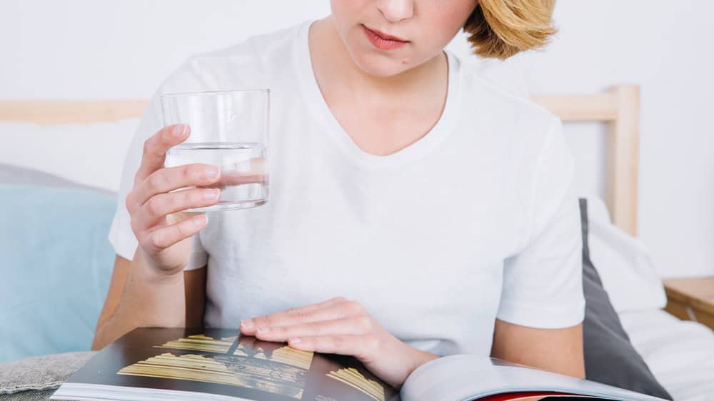 Water Fasting: Benefits, Risks, and How to Do It - crop woman with glass reading magazine 2